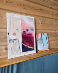Abstract collage paintings on a wooden surface.