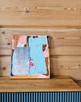 Abstract painting on a wooden surface with a blue and pink abstract design.
