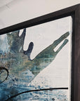 Black floater frames and abstract art piece by Finnish artist Lotta Sirén with black, blue, and white colors on a wall.