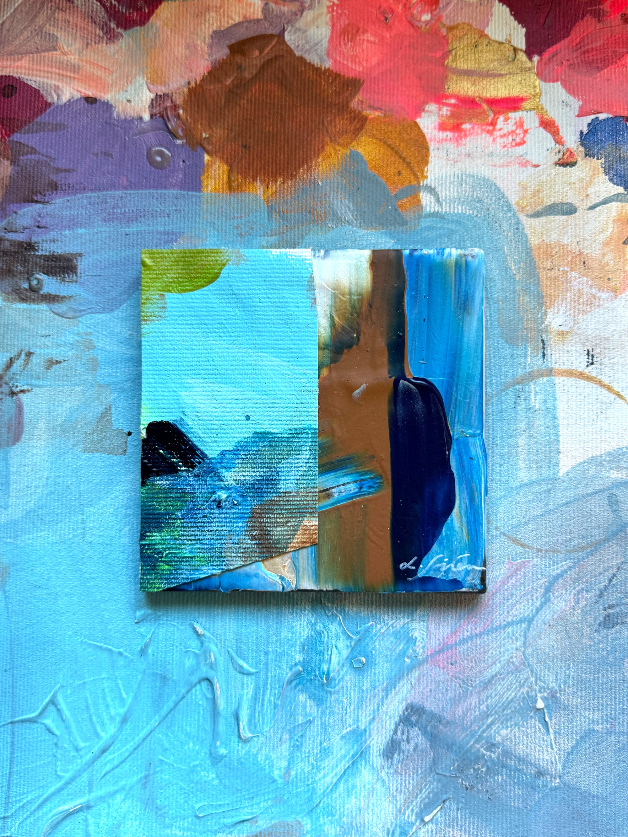 A ceramic abstract painting with a textured blue details and colourful background by artist Lotta Sirén