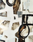Abstract acrylic painting with geometric shapes primarily in black, white, brown, and gray tones on a plywood board.