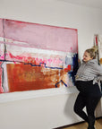 Lotta Sirén standing next to a large abstract painting on a white wall