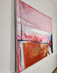 Side profile of an abstract painting by abstract artist Lotta Sirén with pink, orange, and blue on a white wall.