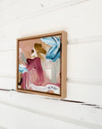 Framed abstract art piece on a white wooden surface
