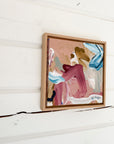 Abstract painting in a wooden frame on a white wall