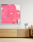 I Don't Like Pink - Limited Edition Canvas Print with white frames on a wall above a TV stand. An Abstract canvas print with bright pink bold strokes and hues of orange, blue and green. Off-white background with black details.