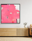 I Don't Like Pink - Limited Edition Canvas Print with black frames on a wall above a TV stand. An Abstract canvas print with bright pink bold strokes and hues of orange, blue and green. Off-white background with black details.