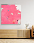 I Don't Like Pink - Limited Edition Canvas Print on a wall above a TV stand. An Abstract canvas print with bright pink bold strokes and hues of orange, blue and green. Off-white background with black details.