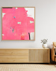 I Don't Like Pink - Limited Edition Canvas Print Print with oak frames on a wall above a TV stand. An Abstract canvas print with bright pink bold strokes and hues of orange, blue and green. Off-white background with black details.