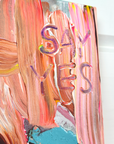 Close-up of a "WHY NOT" colorful abstract painting with 'SAY YES' text