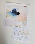 An abstract art print with blue, black, beige, and white brushstrokes, displayed above a Certificate of Authenticity card on a light neutral background.