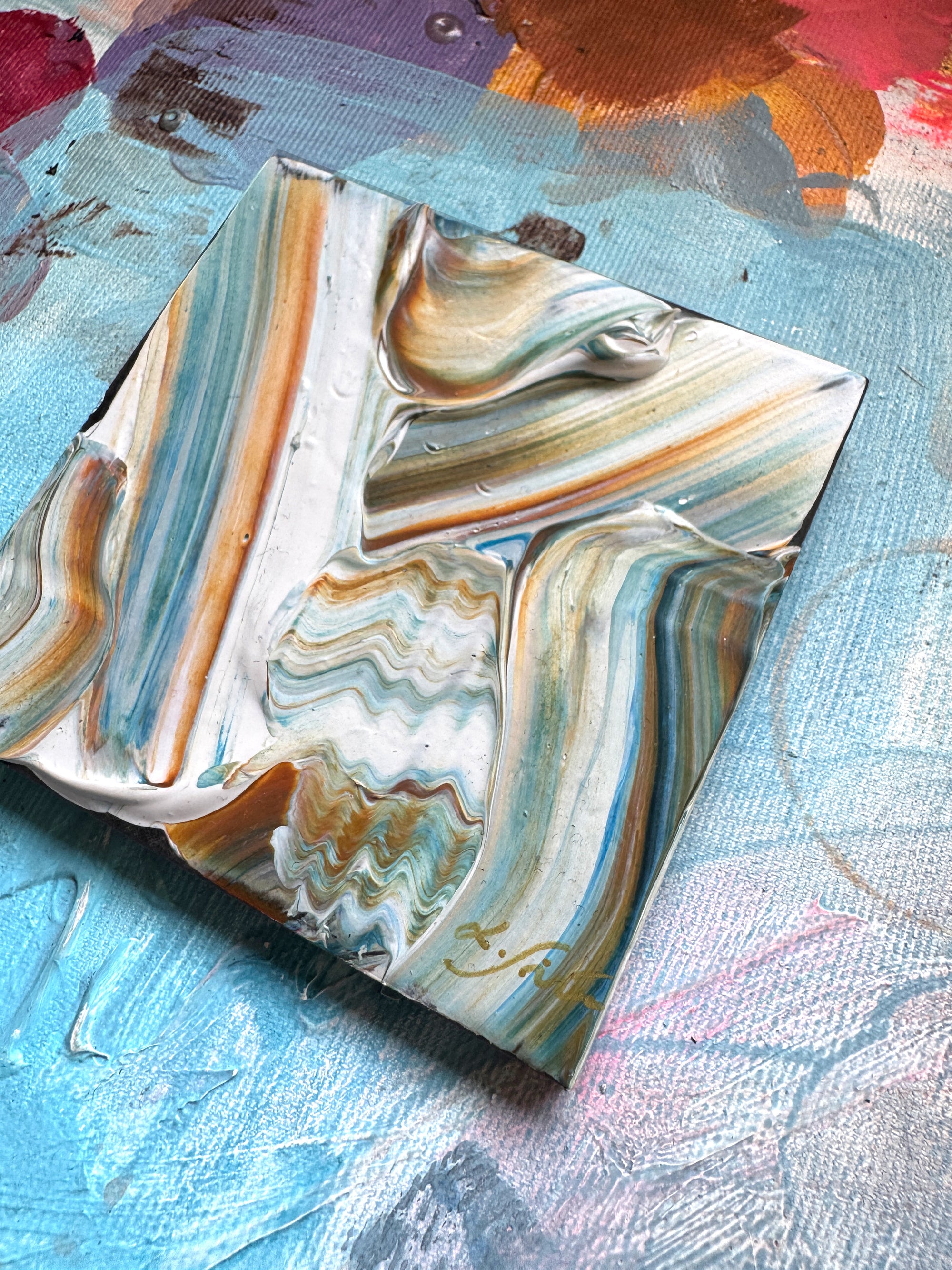 A ceramic abstract artwork with flowy texture and brown, white, and turquoise blue patterns on a textured surface by artist Lotta Sirén.
