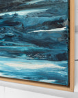 Abstract blue painting with a signature in a wooden frame.
