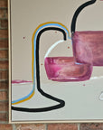 An abstract acrylic painting featuring red and magenta geometric glass shapes, black and yellow curved lines, and a white background, shown hanging on a brick wall.