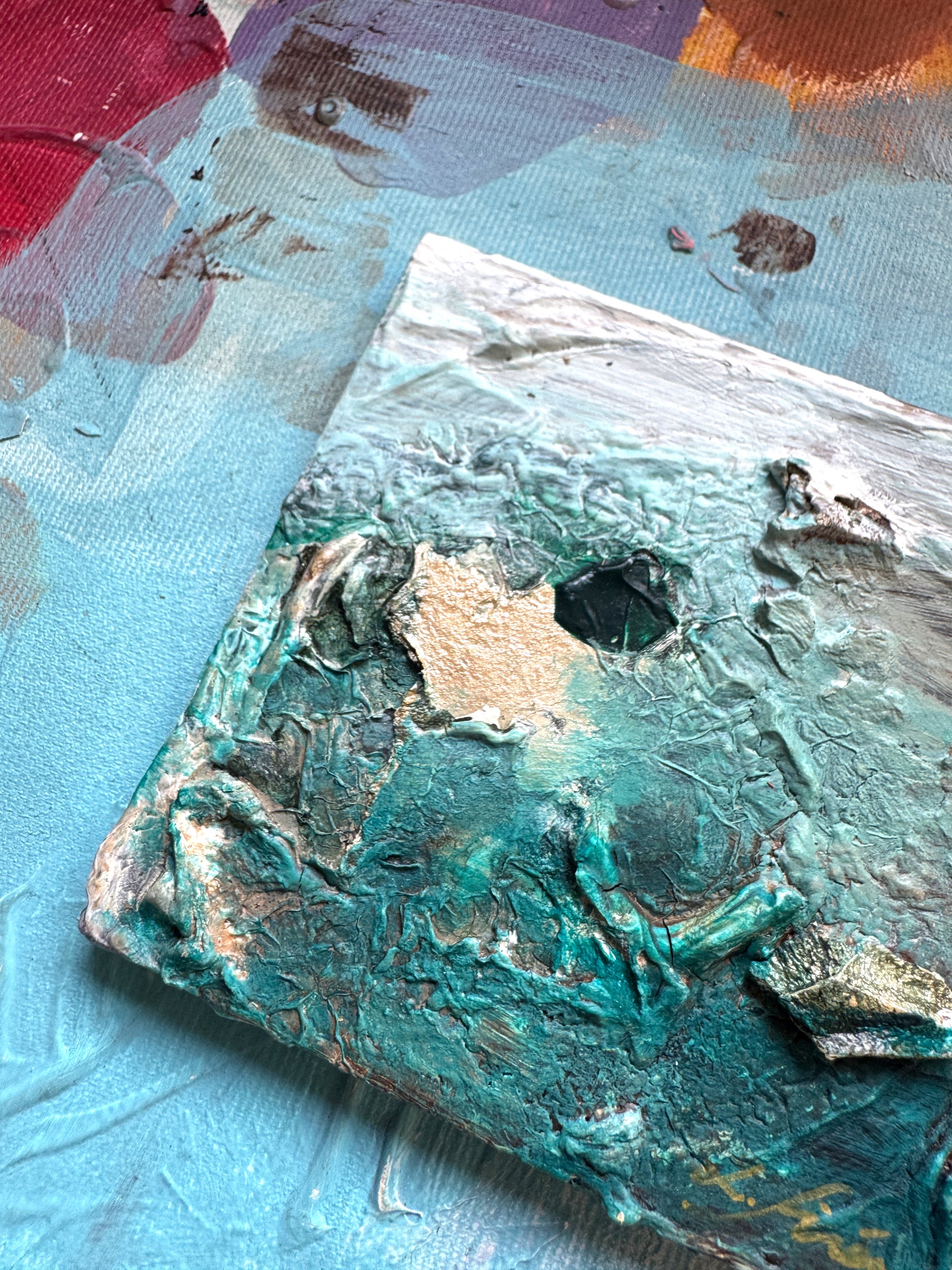 Close-up of a  ceramic abstract painting with a textured green, white. and gold details by artist Lotta Sirén