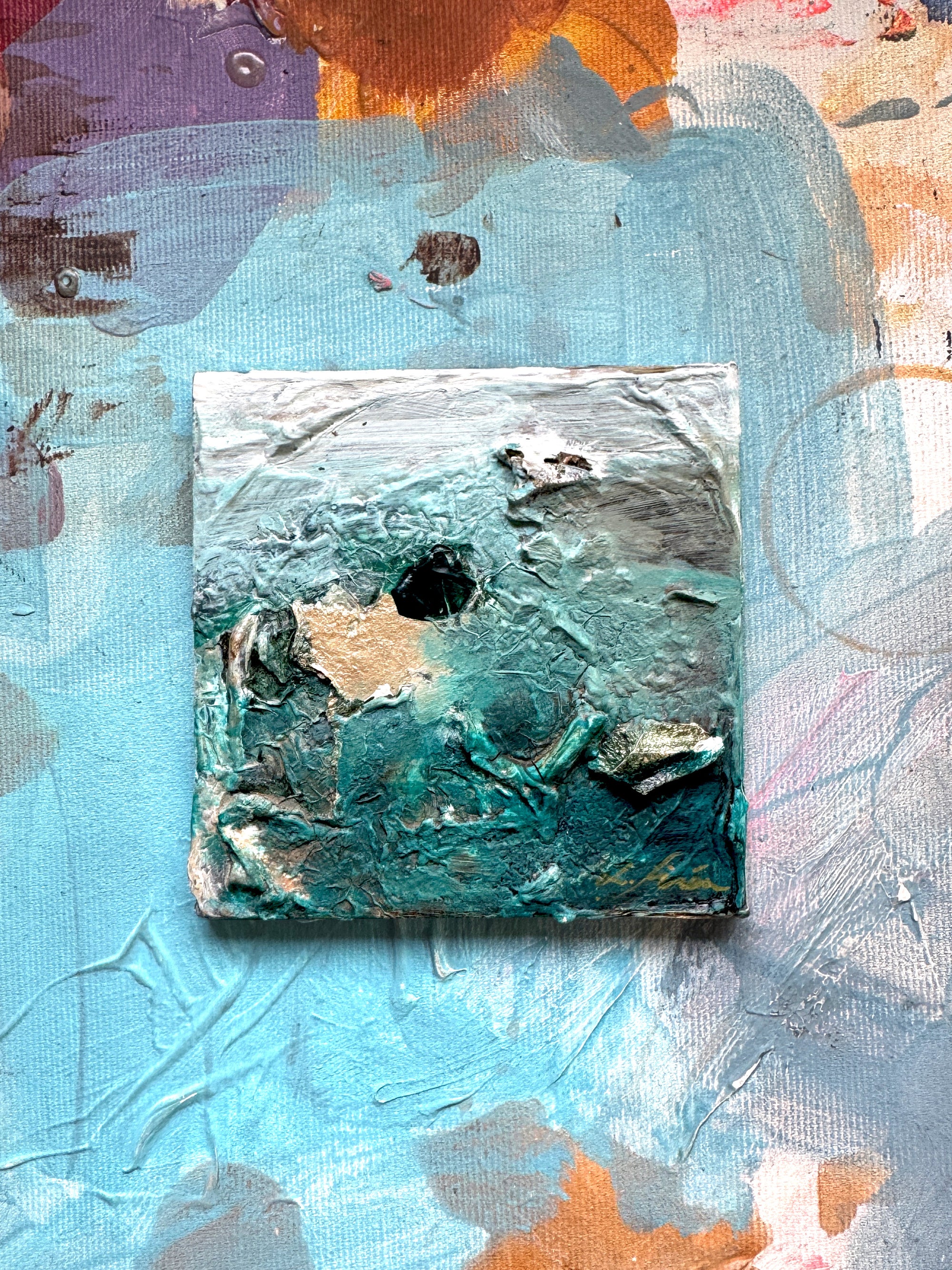 A ceramic abstract painting with a textured green, white. and gold details and colourful background by artist Lotta Sirén