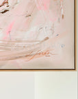 An abstract framed painting featuring soft pink, beige, and white brushstrokes with a signature from artist Lotta Sirén hanging against a white wall.