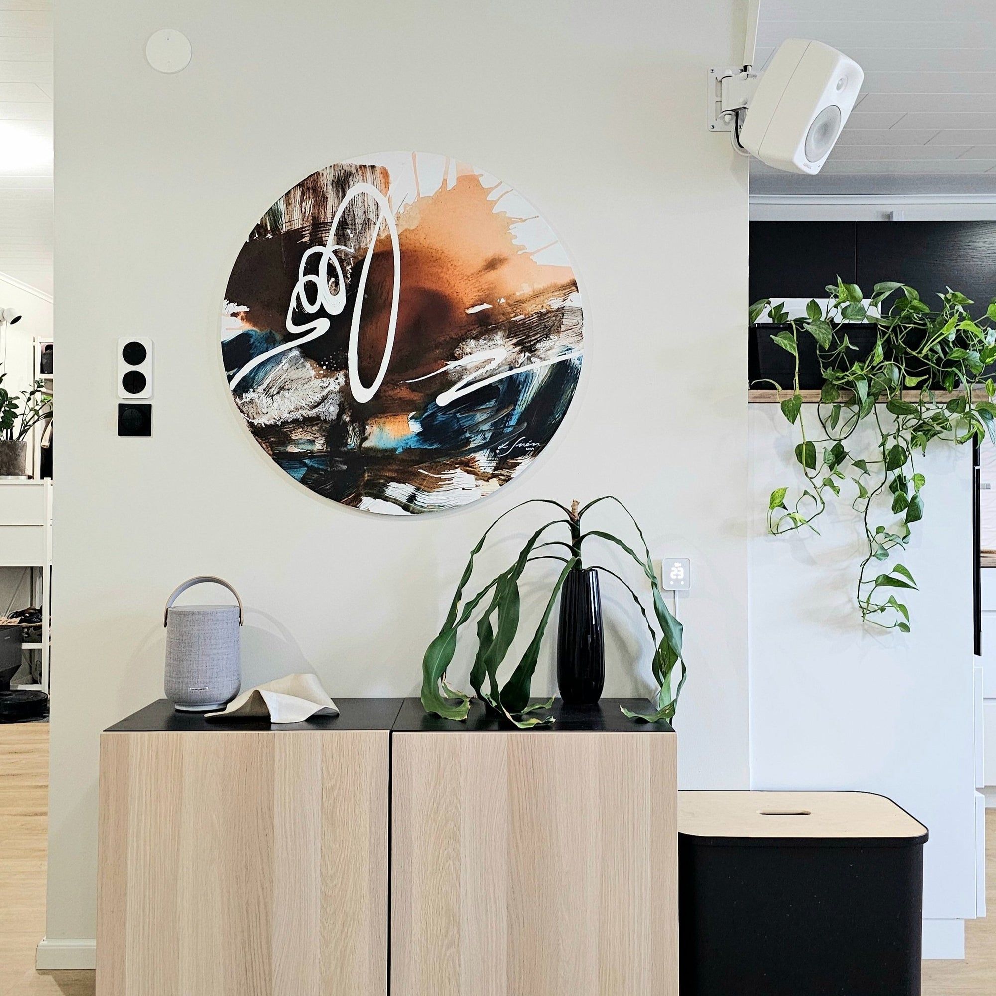 Round abstract painting on a wall in Scandinavian interior.