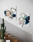 Two abstract art pieces on a wall above a staircase with a cactus plant.