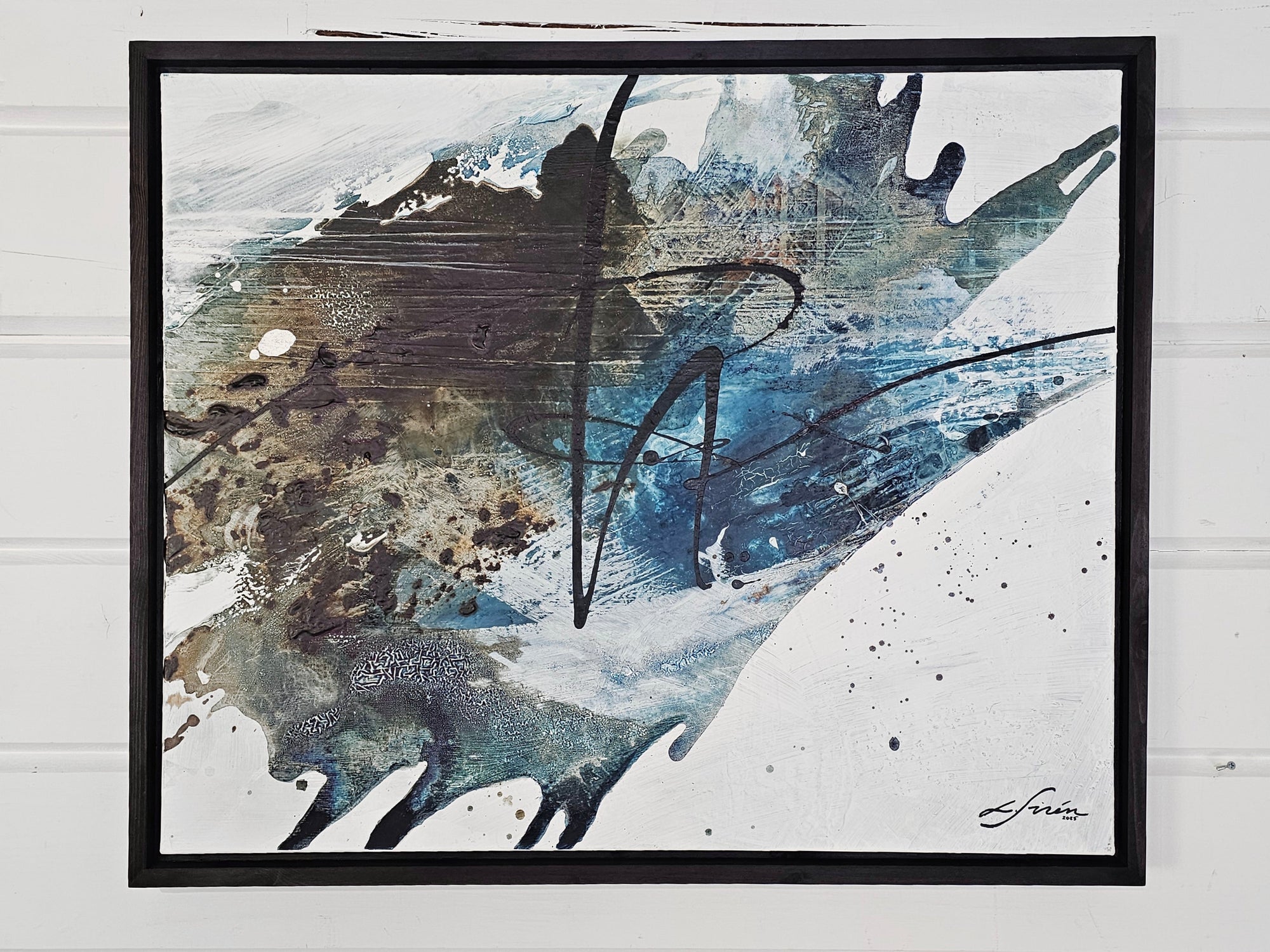 Black floater frames and abstract art piece by Finnish artist Lotta Sirén with black, blue, and white colors on a wall.