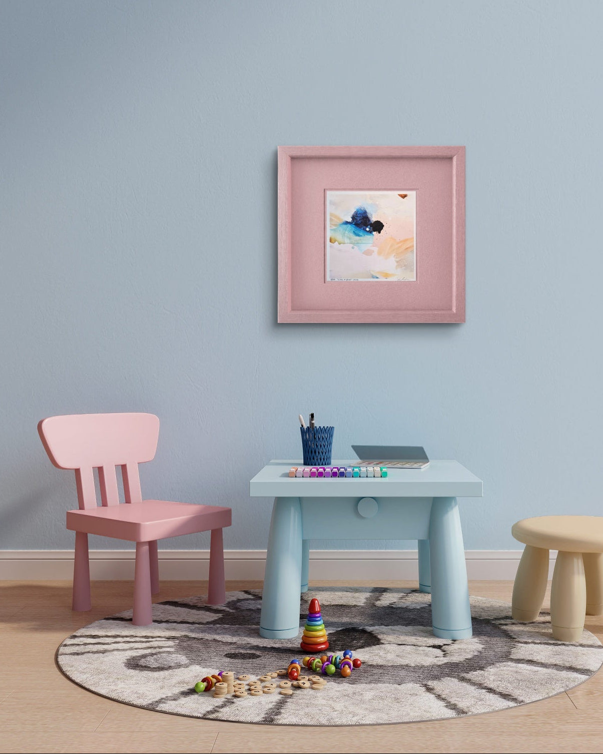A styled children's room corner with a  framed abstract artwork print on the wall above the furniture.