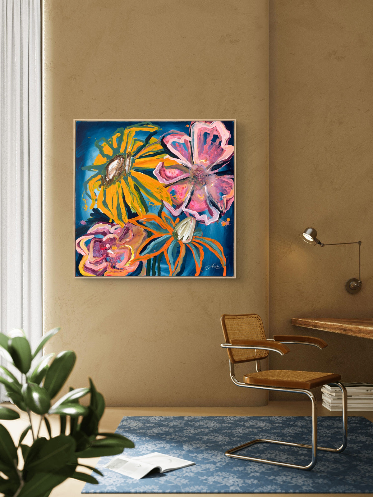 A colorful abstract floral painting hanging on a warm beige wall in a modern room setting with a brown woven chair, blue rug, and a plant in the foreground.