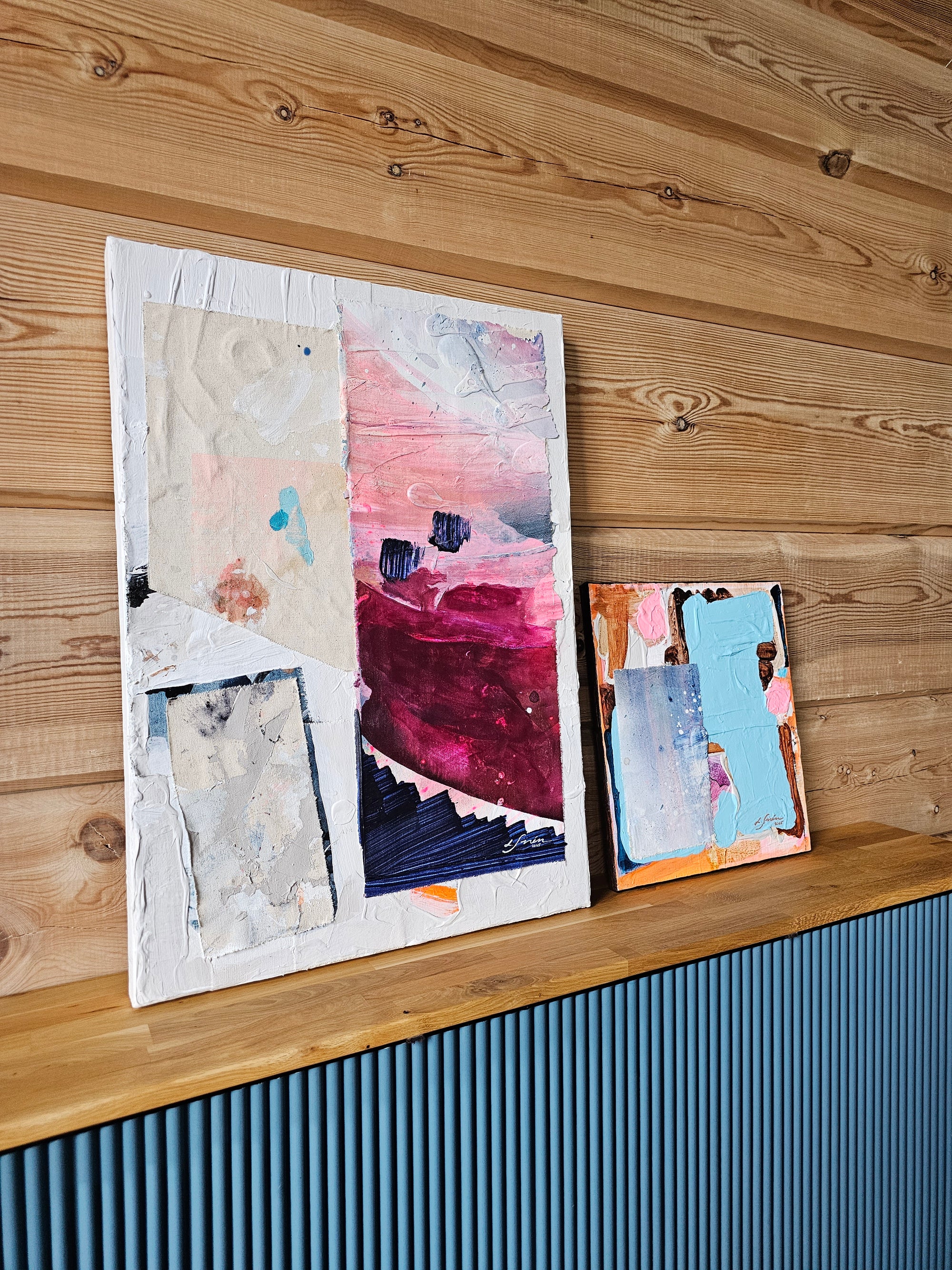Abstract collage paintings on a wooden surface.