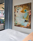 Abstract painting by Lotta Sirén on a wall above a bed in a modern bedroom with a glass wall.