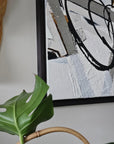 Empowering abstract painting by Lotta Sirén with black and white strokes on a wall, next to a plant and woven basket.
