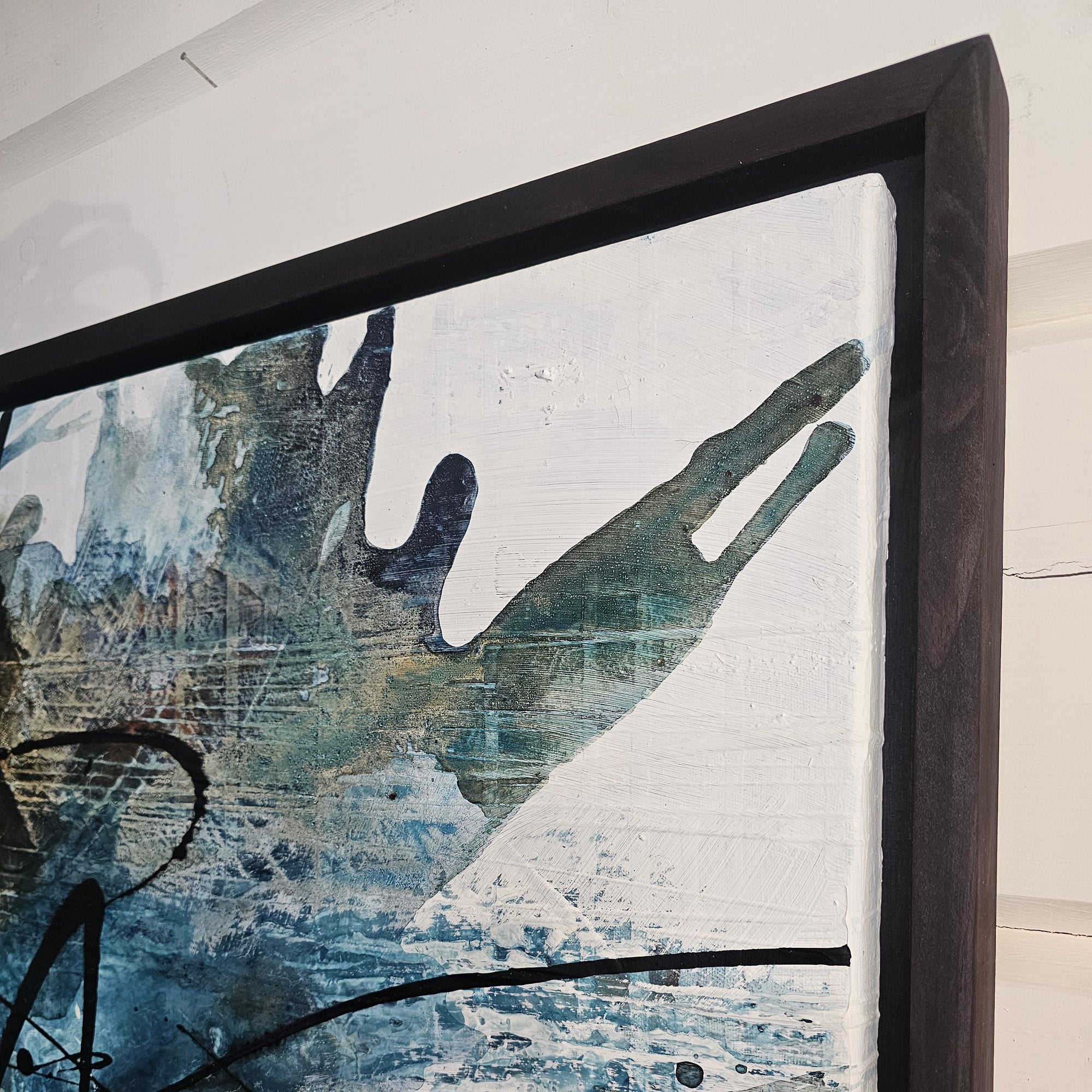 Black floater frames and abstract art piece by Finnish artist Lotta Sirén with black, blue, and white colors on a wall.