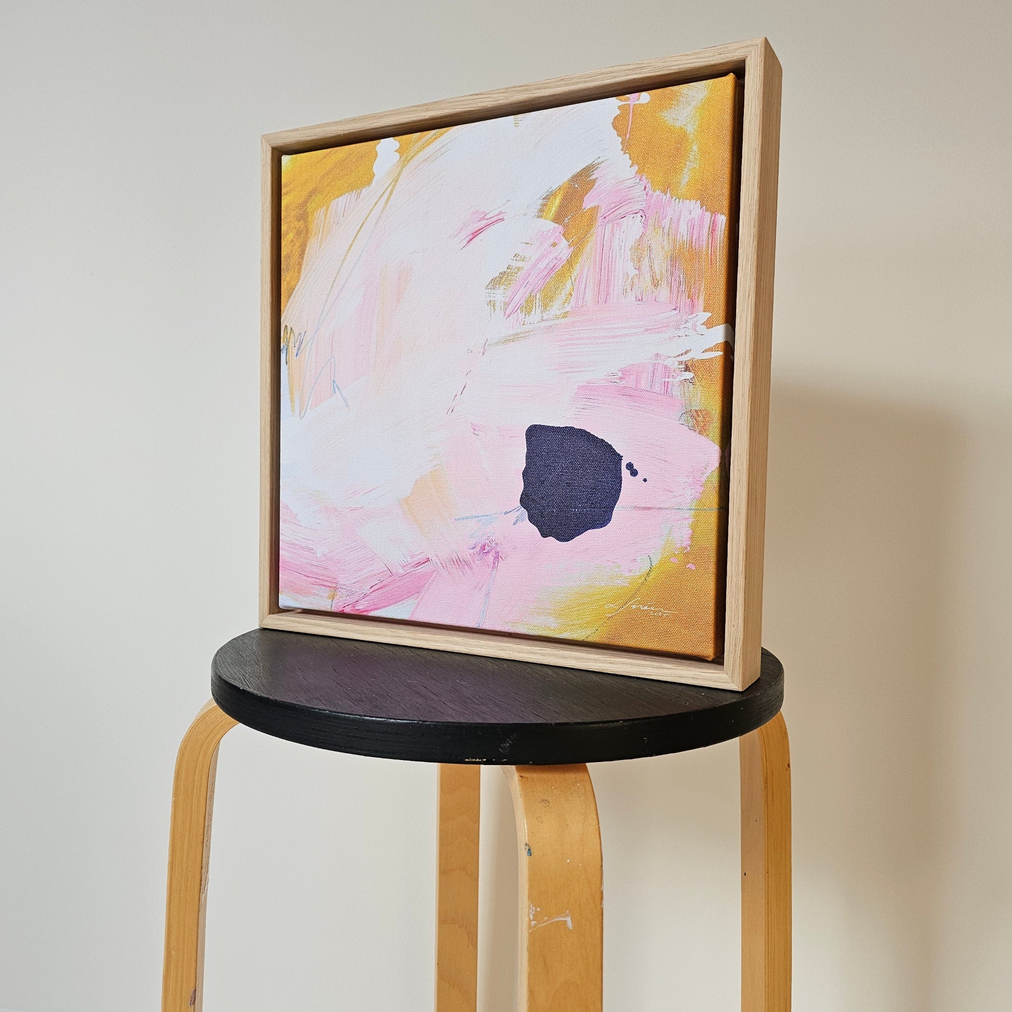 Framed abstract art print on a wooden stool.