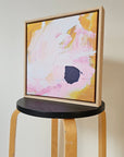 Framed abstract art print on a wooden stool.