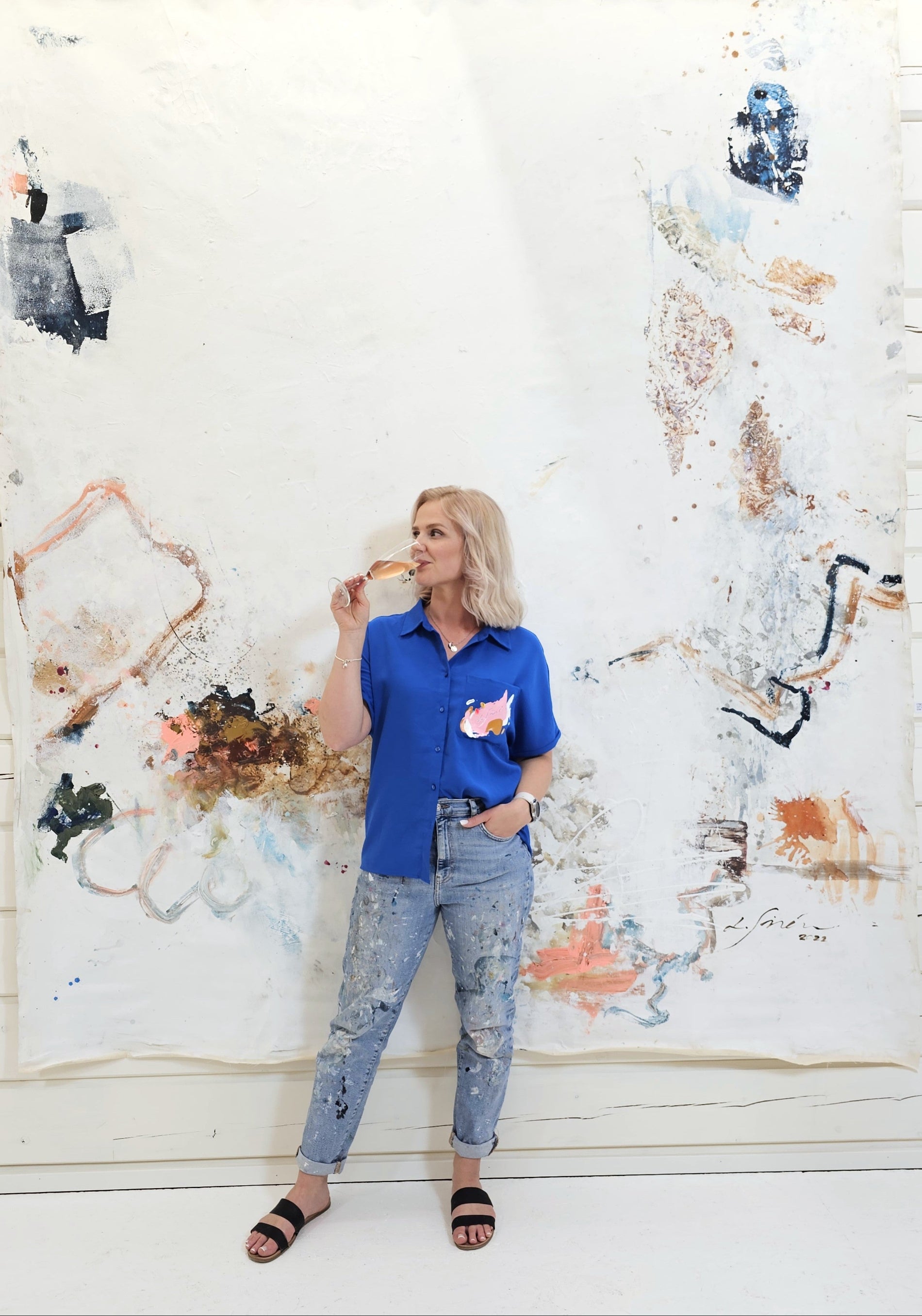 Artist Lotta Sirén in front of her large white painting.