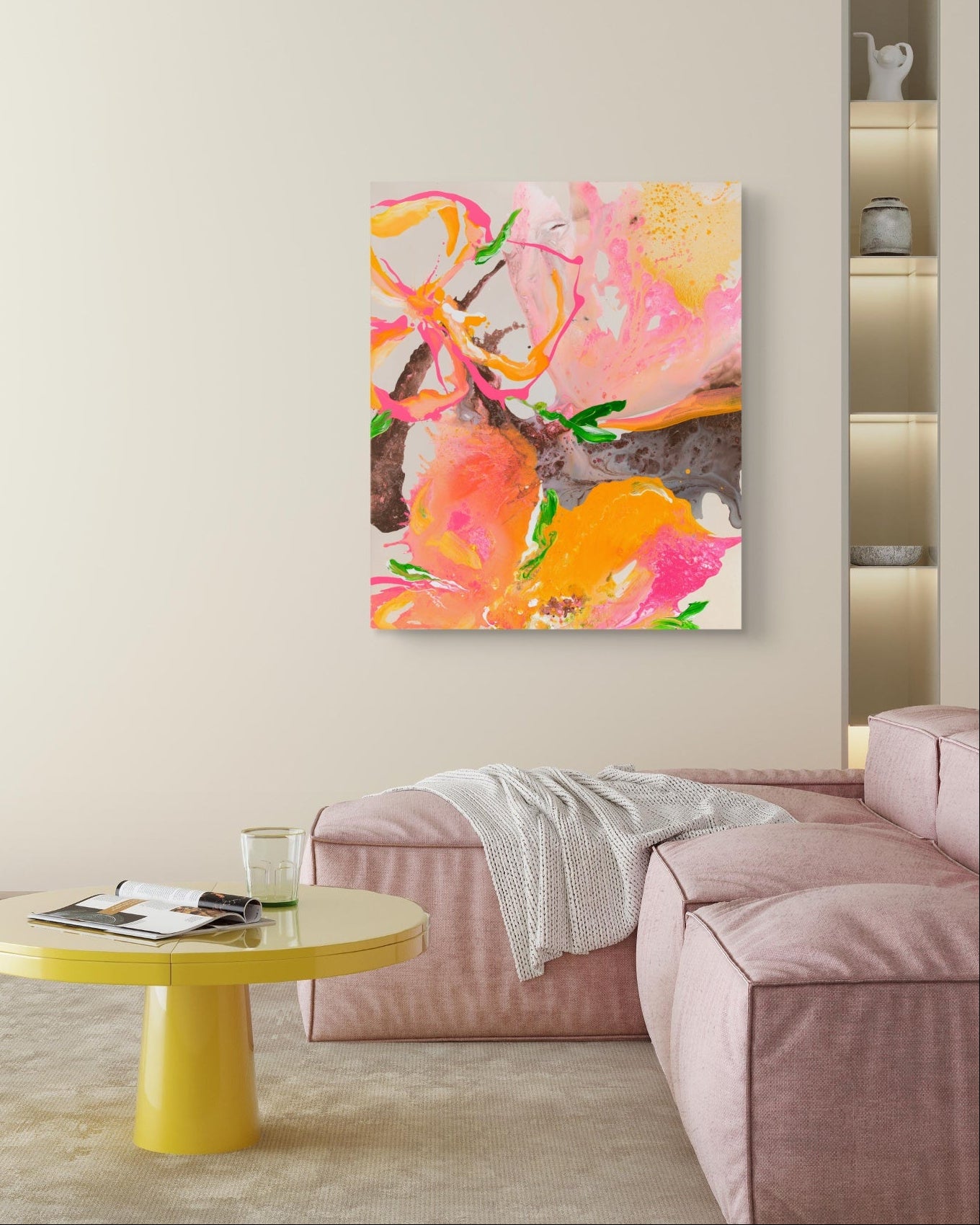 An abstract canvas painting featuring vibrant pink, orange, yellow, and green brushstrokes, displayed in a modern living room setting above a pink sofa and a yellow side table.