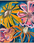 An abstract floral painting featuring large stylized flowers in yellow, pink, orange, and white on a deep blue background, framed in light wood.