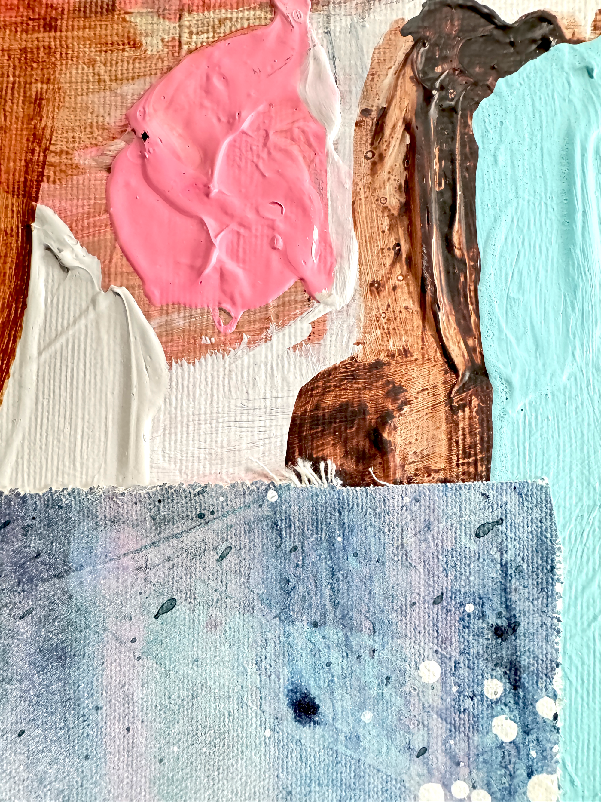 Close-up of textured paint swatches in pink, white, brown, and blue on a wooden surface.