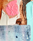 Close-up of textured paint swatches in pink, white, brown, and blue on a wooden surface.
