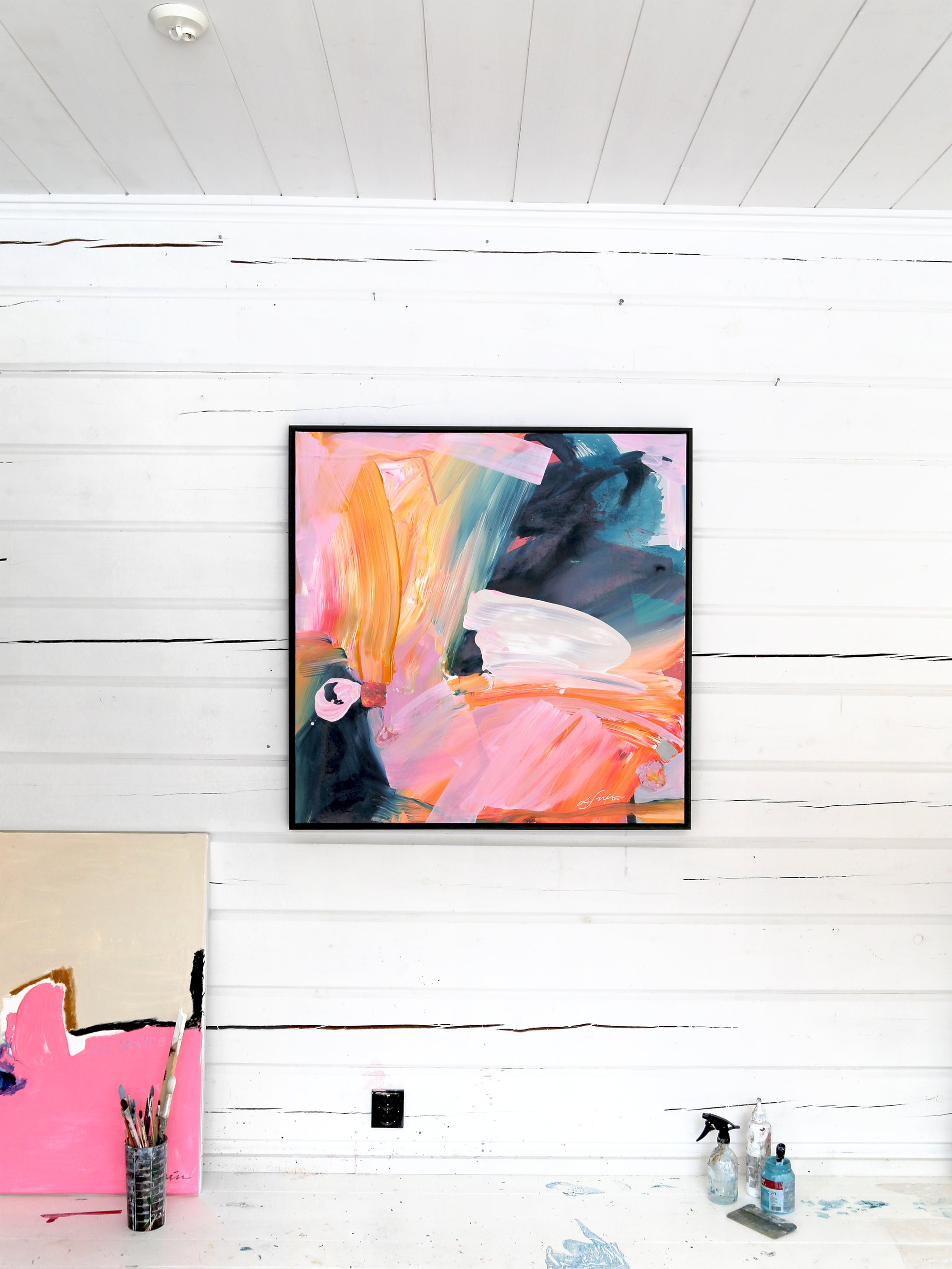 Abstract painting on a white wall with art supplies below by Finnish artist Lotta Sirén