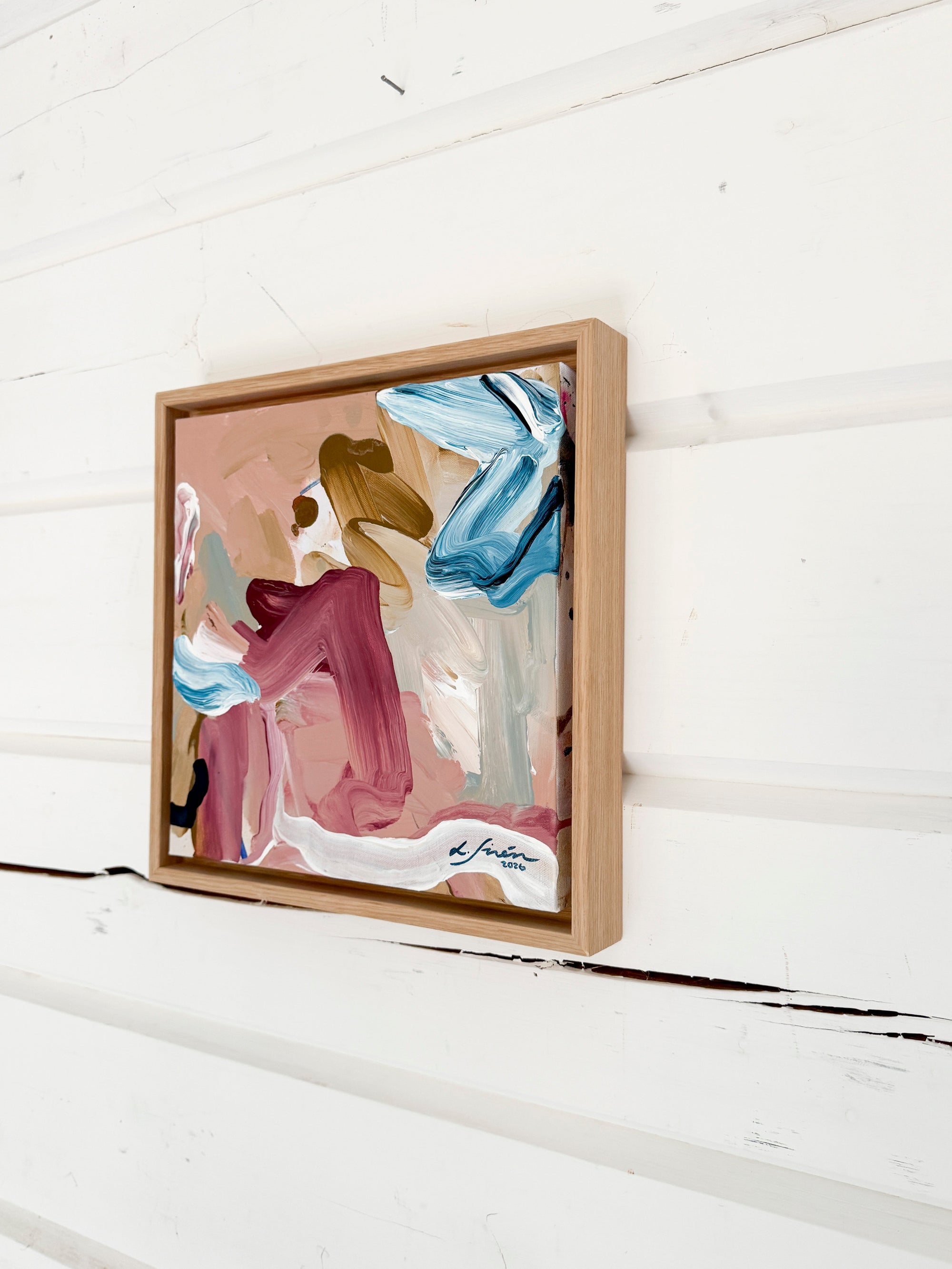 Framed abstract art piece on a white wooden surface