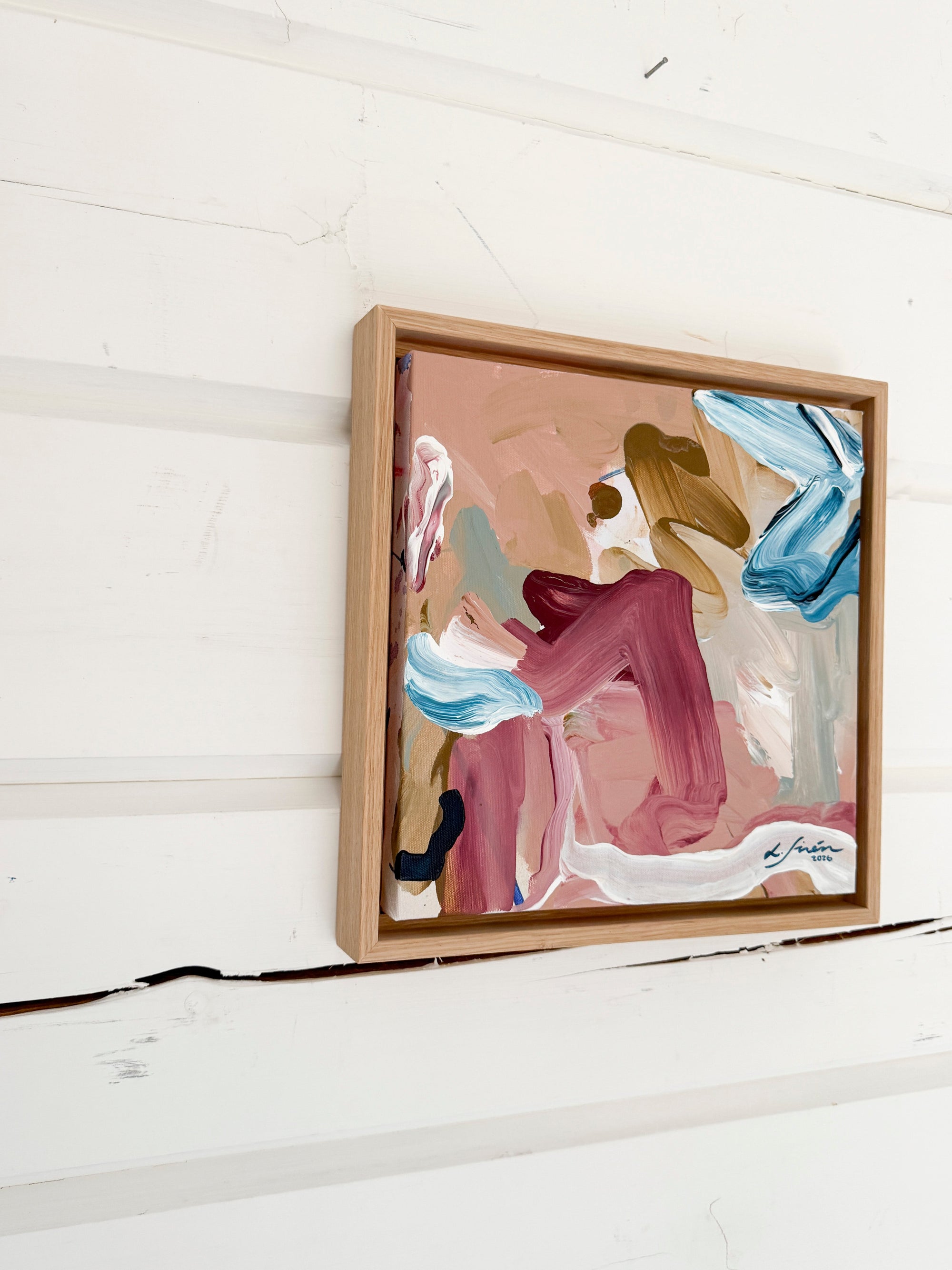 Abstract painting in a wooden frame on a white wall