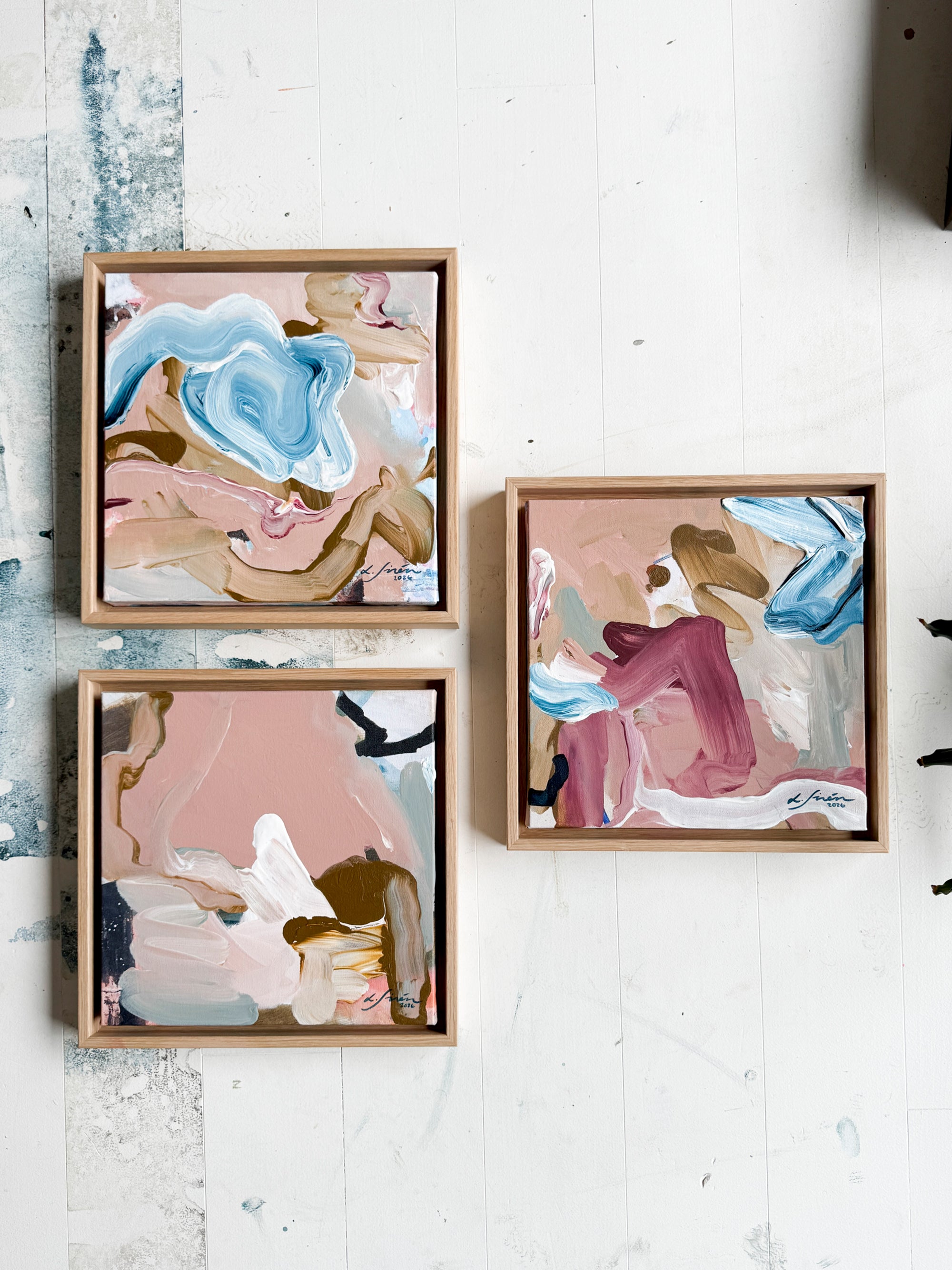 Three abstract art pieces in wooden frames on a white surface by Finnish artist Lotta Sirén