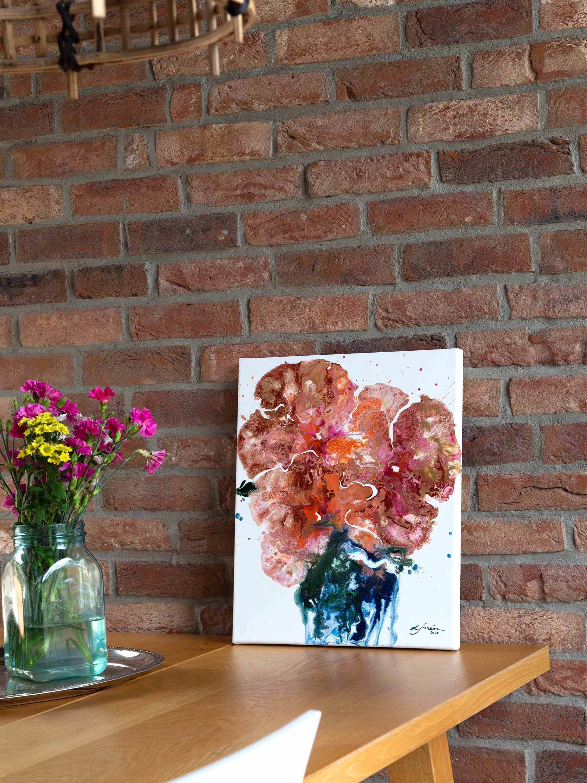 Colorful semi-abstract painting on a table leaning against a brick wall  by Finnish artist Lotta Sirén