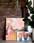 Colorful semi-abstract paintings leaning against a brick wall with a plant in the foreground by Finnish artist Lotta Sirén
