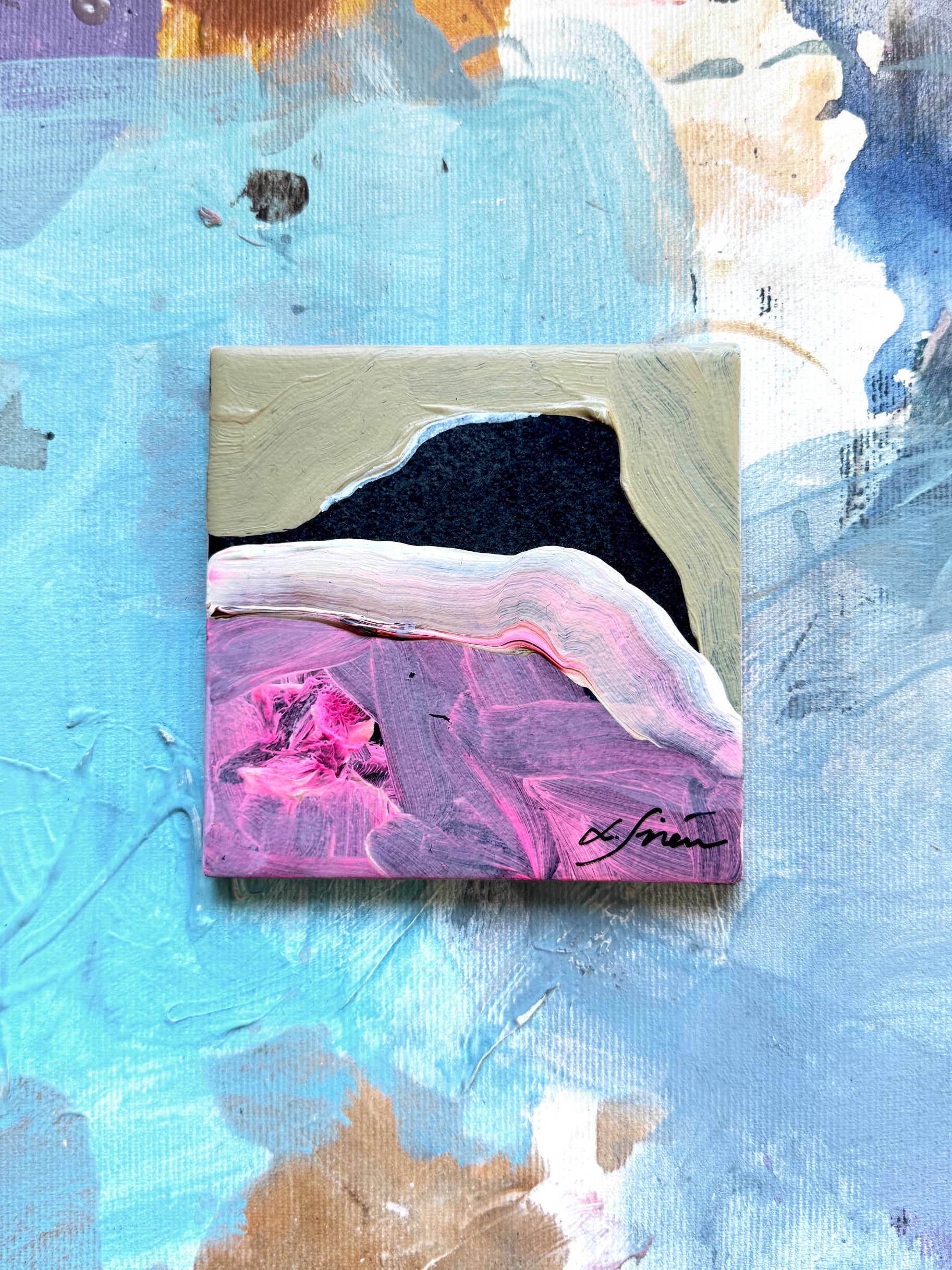 Small ceramic abstract artwork on a textured blue background with colorful brush strokes