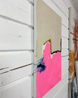 A side of an abstract painting with pink and black elements on a white wall