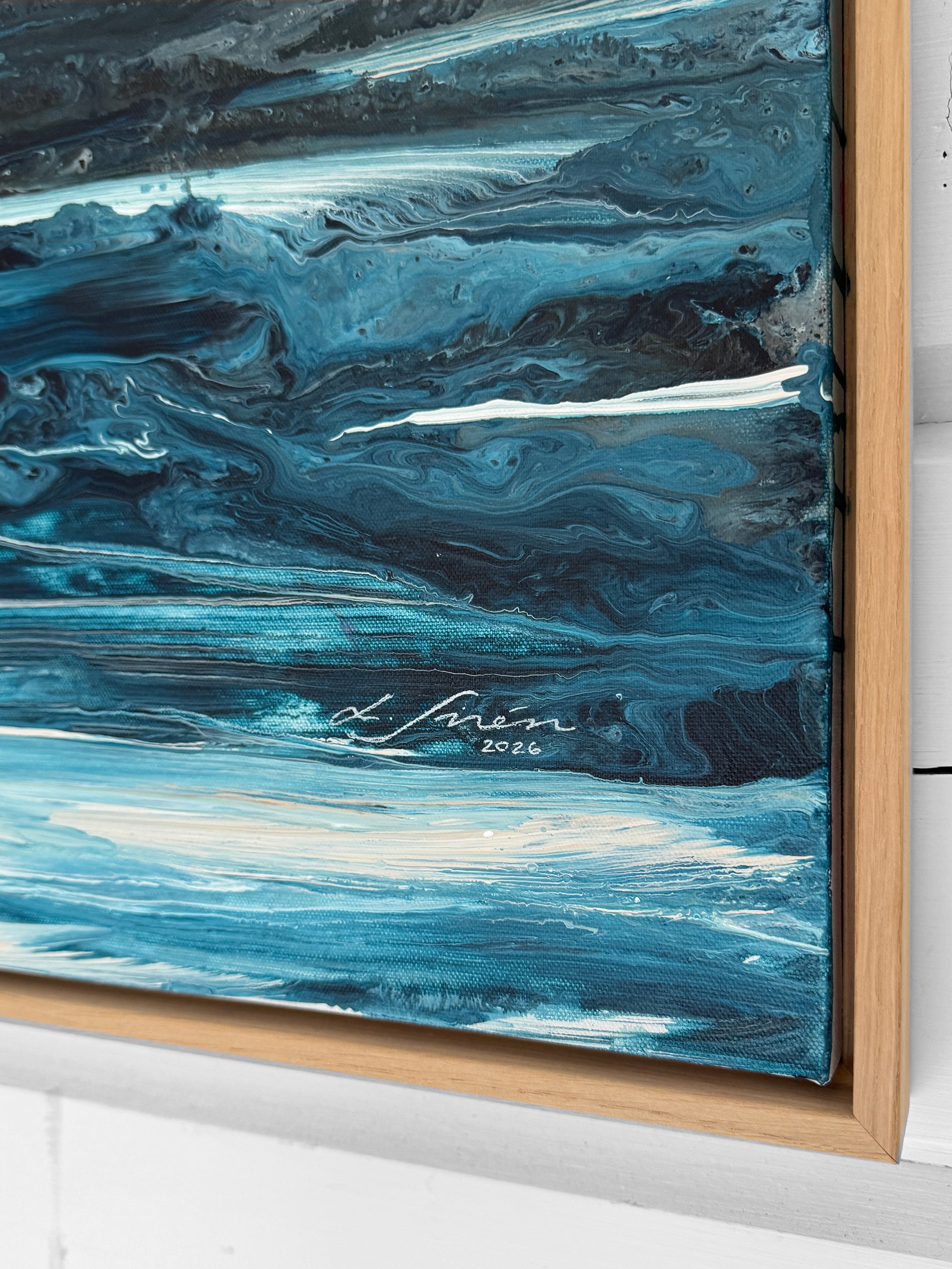 Abstract blue painting with a signature in a wooden frame.