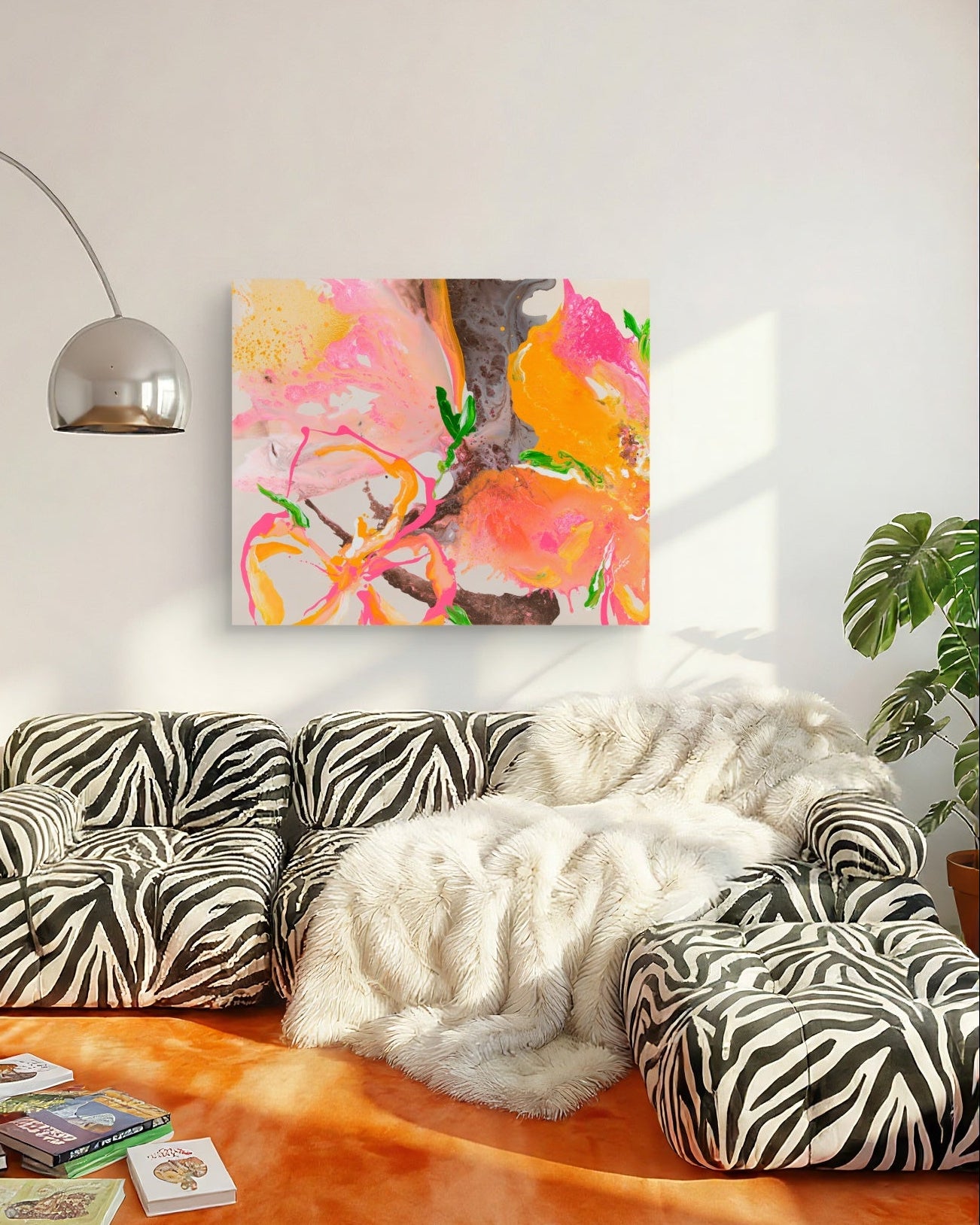 A colorful abstract painting with pink, orange, yellow, and green brushstrokes hangs on a white wall above a modern zebra-print sectional sofa with a white faux-fur throw blanket.