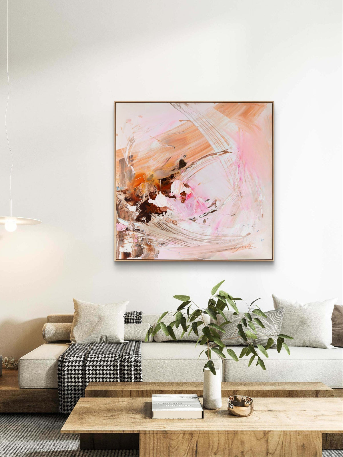An abstract painting with pink, orange, and brown brushstrokes hanging on a white wall above a modern white sofa in a styled living room.