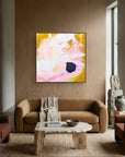 Living room with a brown sofa, coffee table, and yellow abstract painting on a wooden wall.