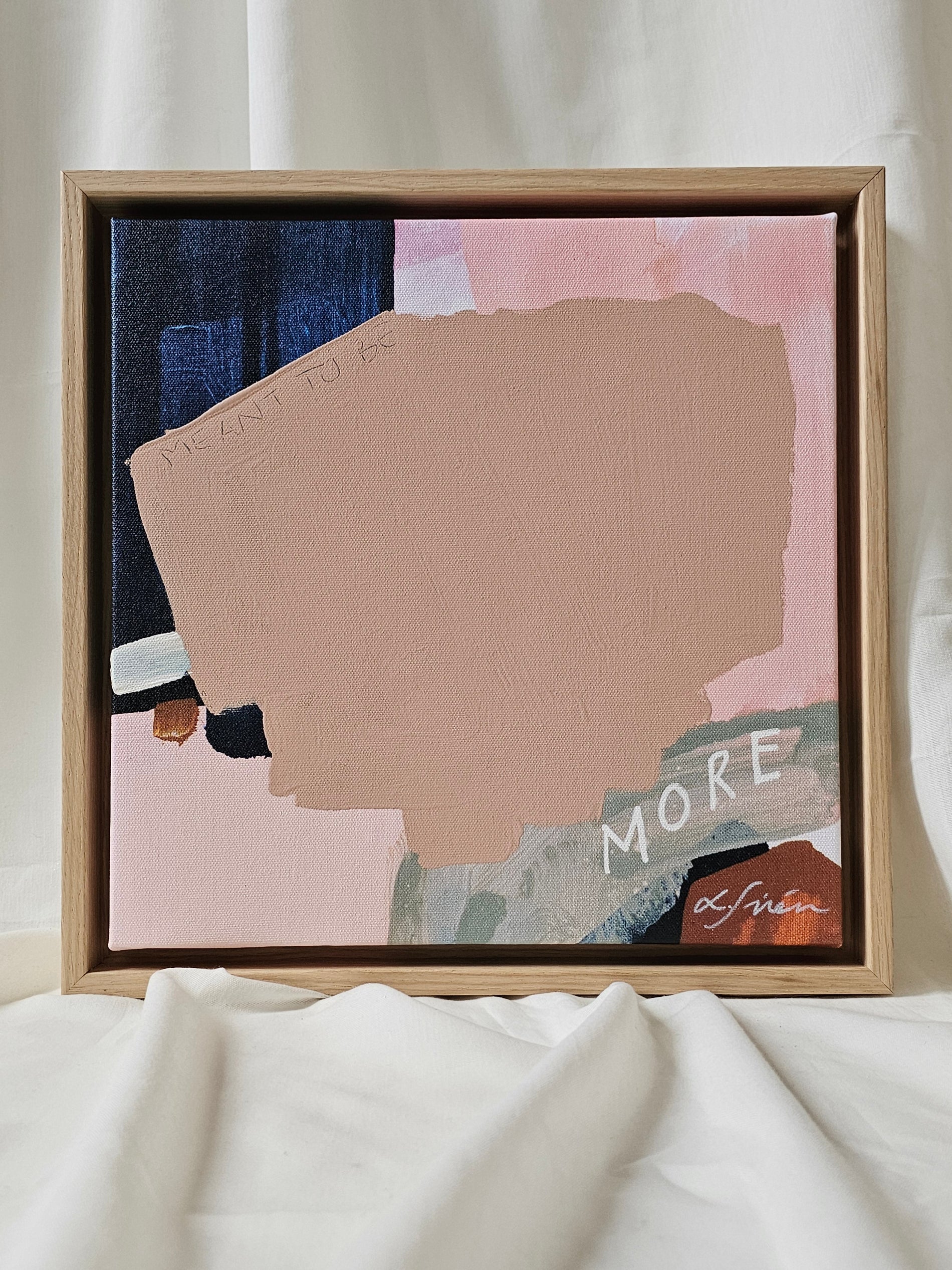 Framed abstract art piece with 'MORE' text on a neutral background